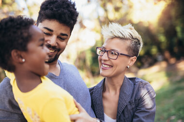 Happy diverse couple with young child in the park